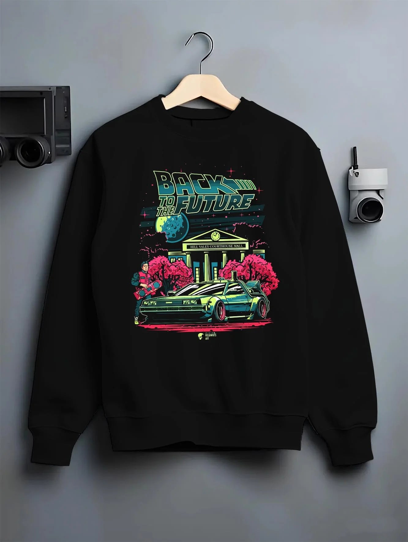 Black crewneck sweatshirt on a hanger against a grey wall, featuring DeLorean DMC-12 street retro classic racing graphic.