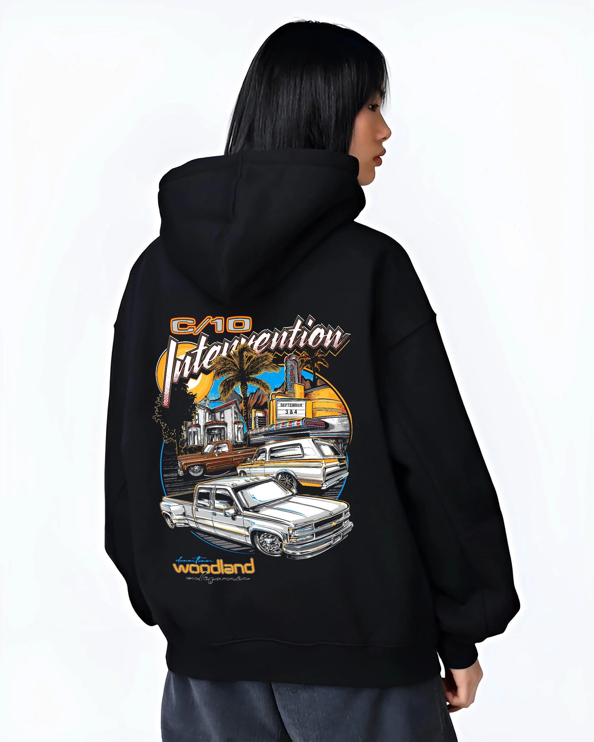 Black hoodie worn by a female model, back view, featuring Chevrolet C10 retro vintage classic racing street performance graphic.