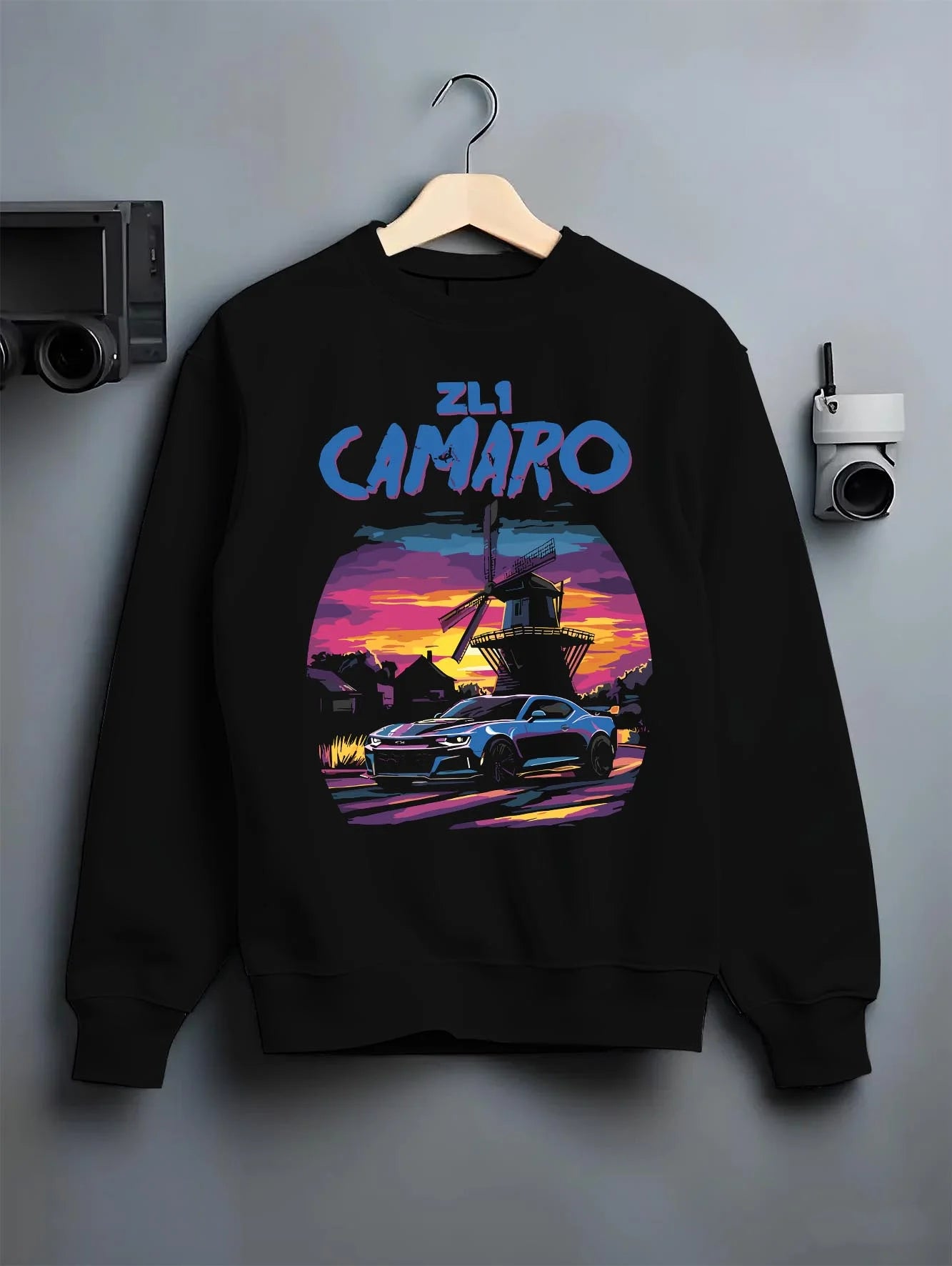 Black crewneck sweatshirt on a hanger against a grey wall, featuring Chevrolet Camaro rs racing nascar motorsport american graphic.