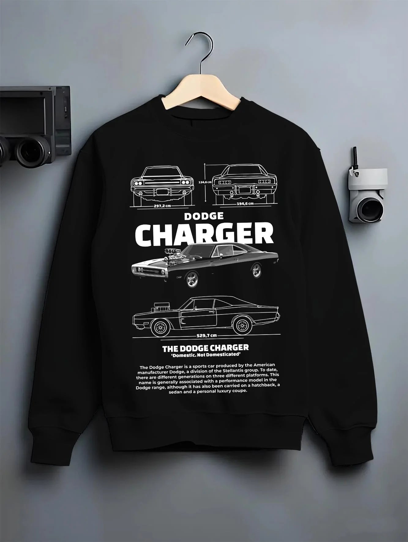Black crewneck sweatshirt on a hanger against a grey wall, featuring Dodge Charger rs muscle street retro classic graphic.