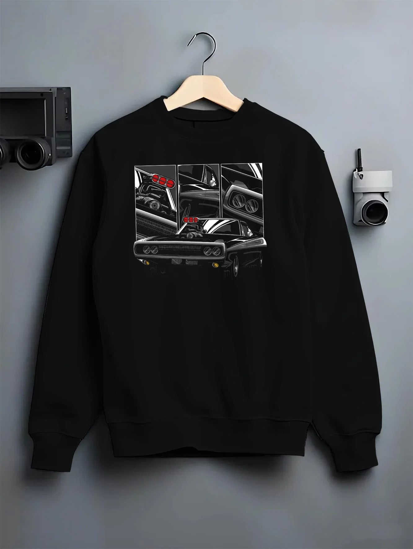 Black crewneck sweatshirt on a hanger against a grey wall, featuring Dodge Charger supercharged american muscle classic graphic.