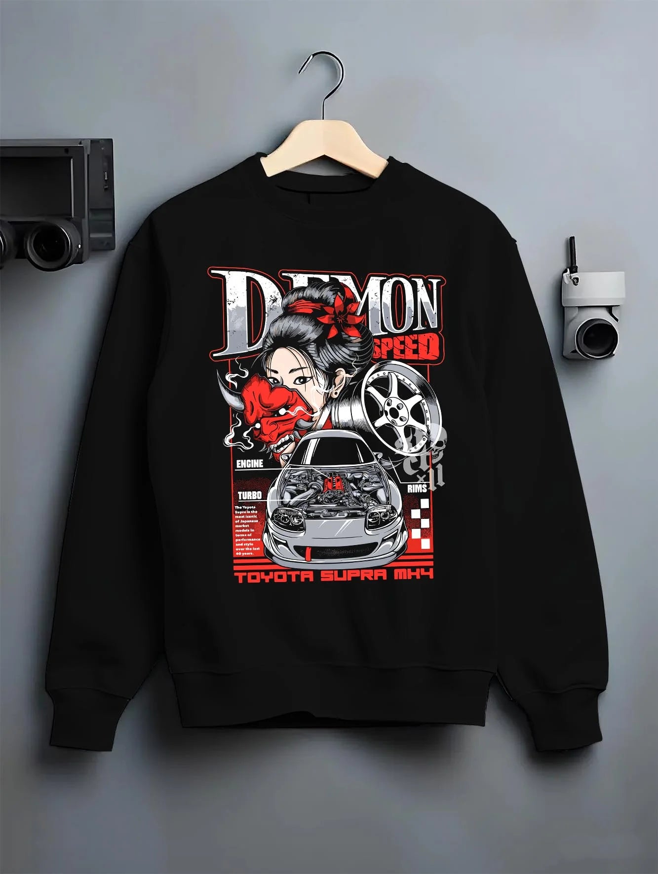 Black crewneck sweatshirt on a hanger against a grey wall, featuring Toyota Supra turbo racing drift jdm japanese tuner graphic.