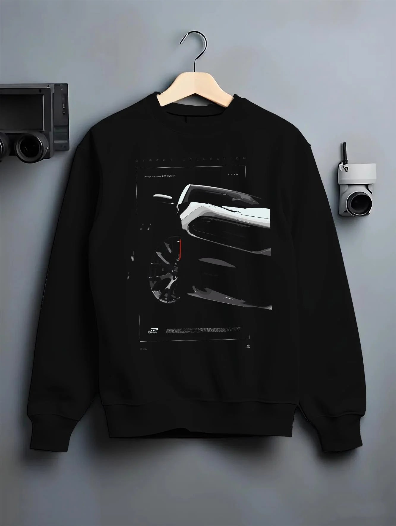 Black crewneck sweatshirt on a hanger against a grey wall, featuring Dodge Charger racing muscle street enthusiast graphic.