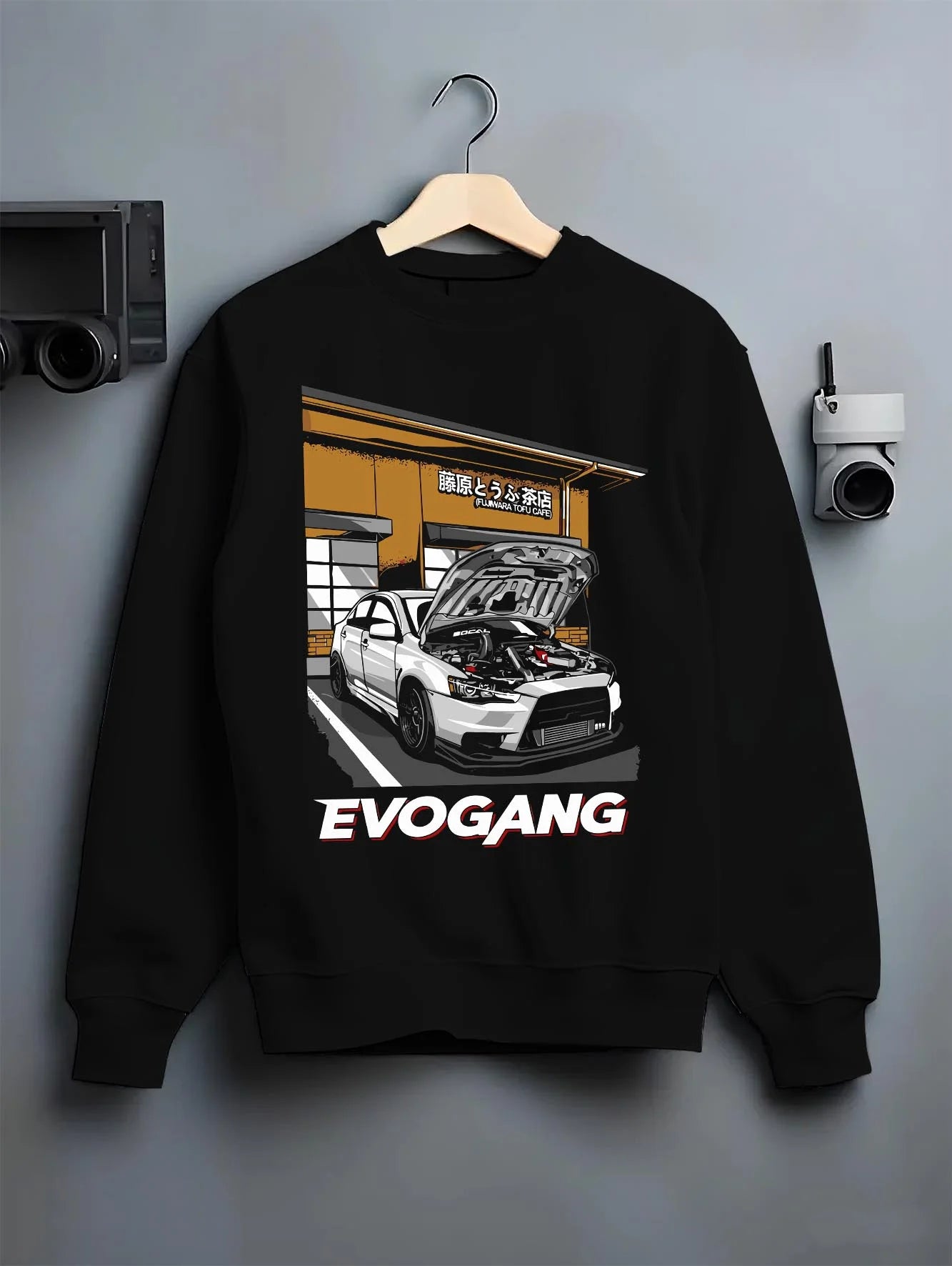 Black crewneck sweatshirt on a hanger against a grey wall, featuring Mitsubishi EVO rs racing jdm tuner street performance graphic.