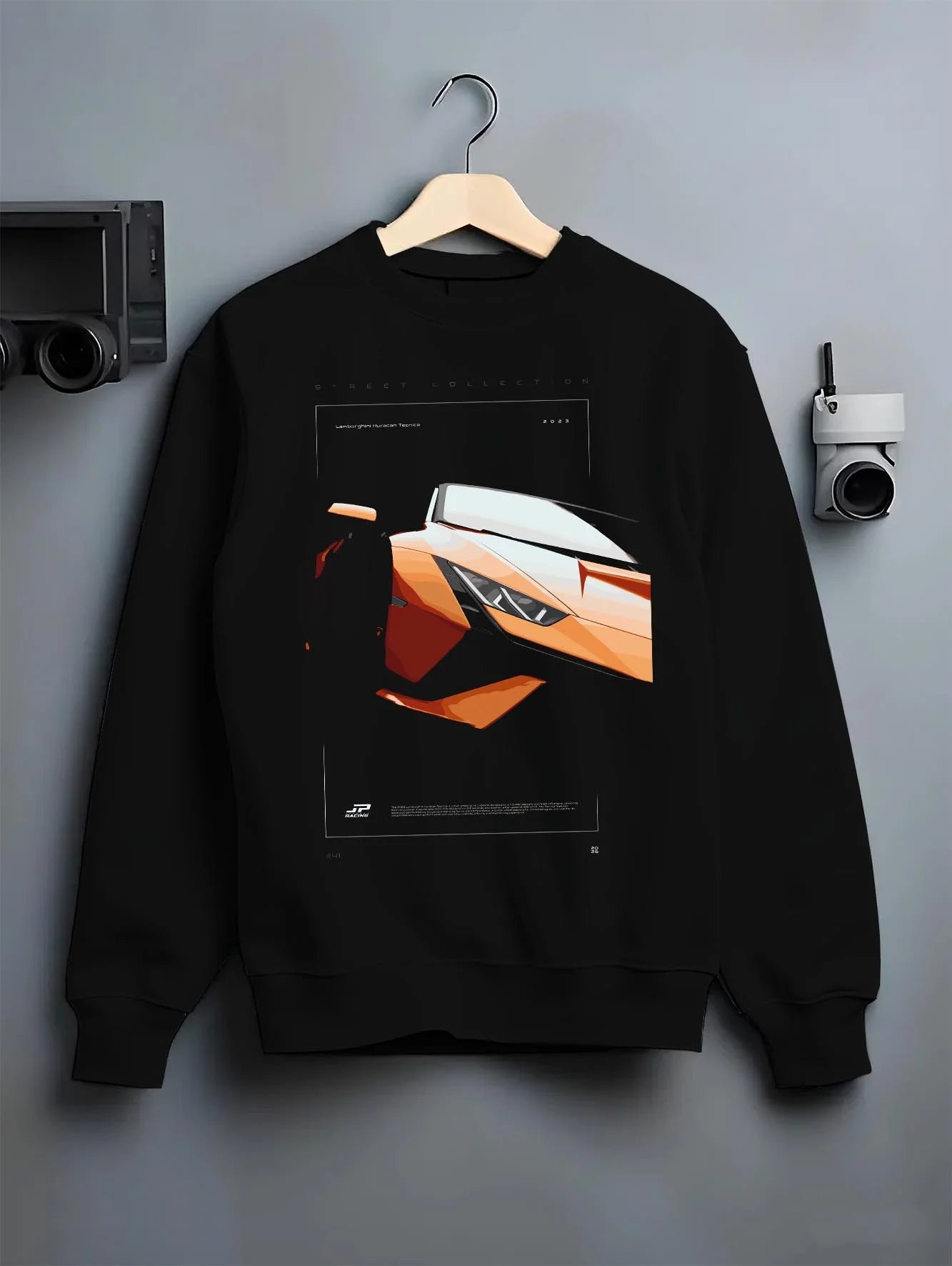 Black crewneck sweatshirt on a hanger against a grey wall, featuring Lamborghini Huracan street racing performance graphic.