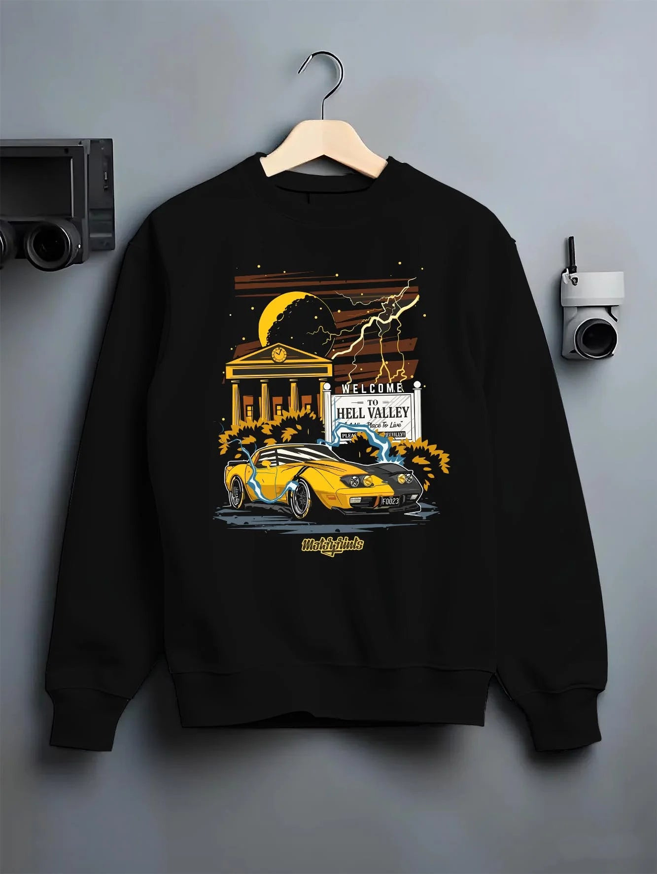 Black crewneck sweatshirt on a hanger against a grey wall, featuring racing street retro performance motorsport automotive graphic.