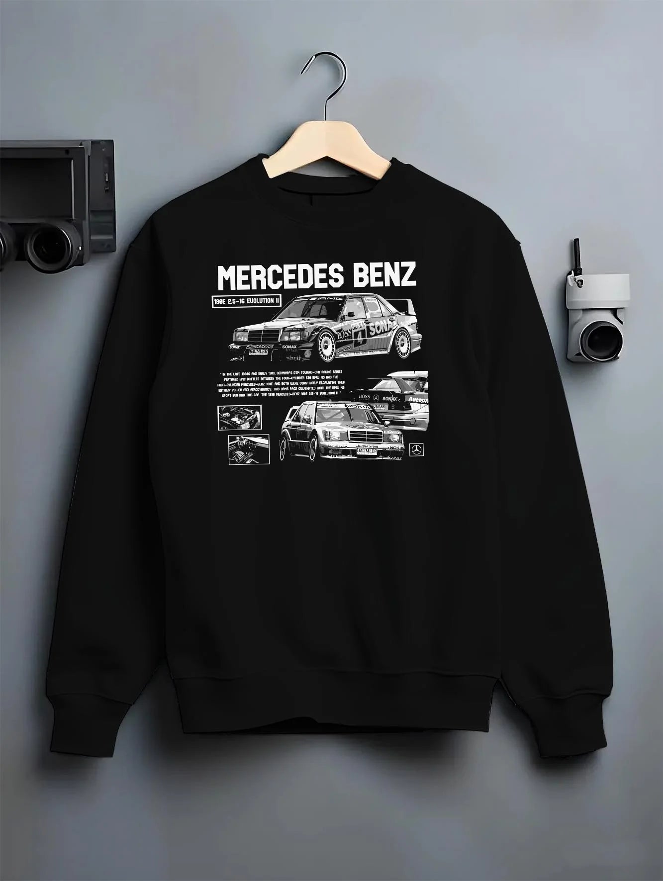 Black crewneck sweatshirt on a hanger against a grey wall, featuring Mercedes-Benz AMG rs racing motorsport street meramg.