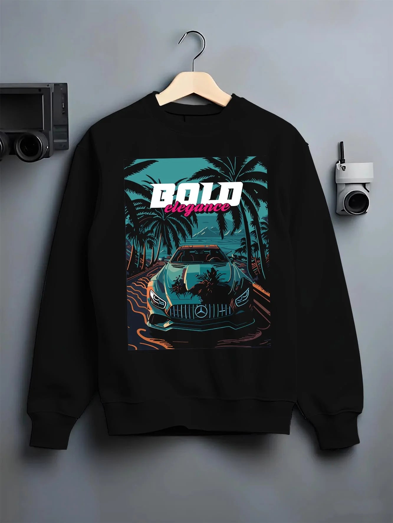 Black crewneck sweatshirt on a hanger against a grey wall, featuring Mercedes-Benz street retro racing performance graphic.