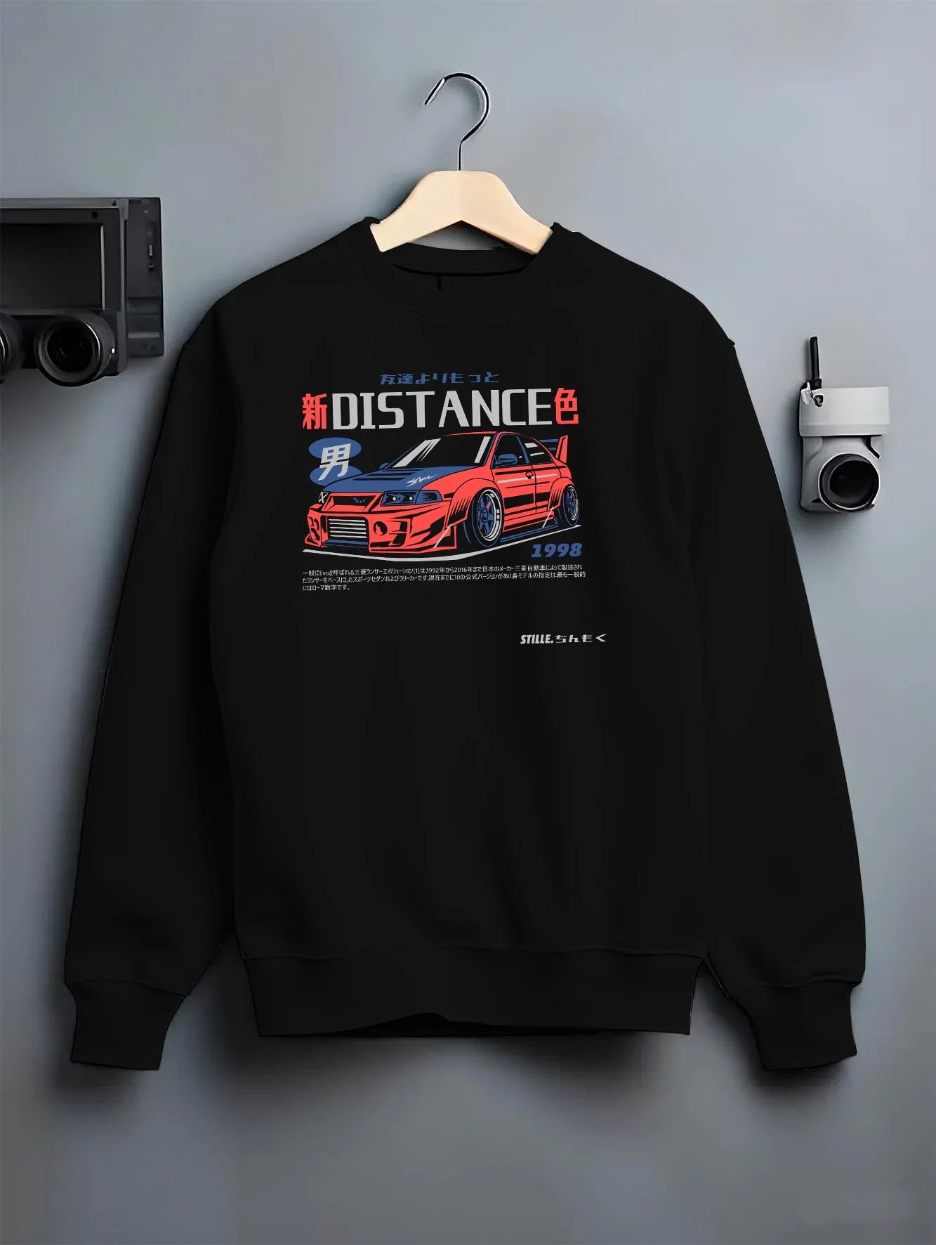 Black crewneck sweatshirt on a hanger against a grey wall, featuring Mitsubishi EVO turbo racing drift jdm japanese street graphic.