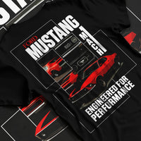 Black T-shirt laid flat with natural fabric folds, featuring MUSTANG racing drag american muscle street classic enthusiast graphic.