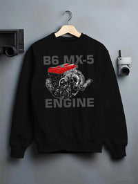 Black crewneck sweatshirt on a hanger against a grey wall, featuring Mazda MX-5 jdm tuner street racing performance graphic.