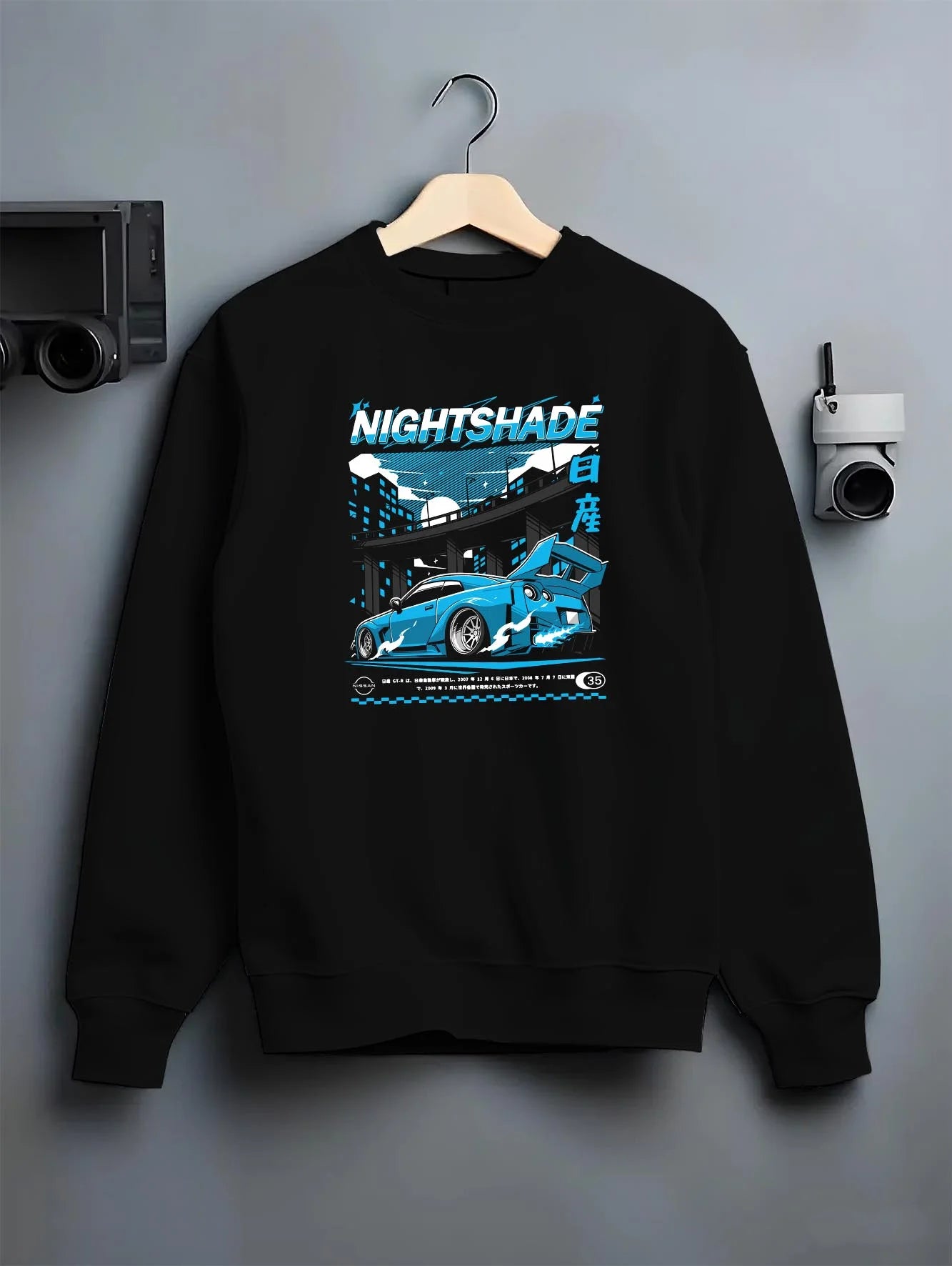 Black crewneck sweatshirt on a hanger against a grey wall, featuring Nissan GT-R R35 gt r r35 skyline racing drift jdm graphic.