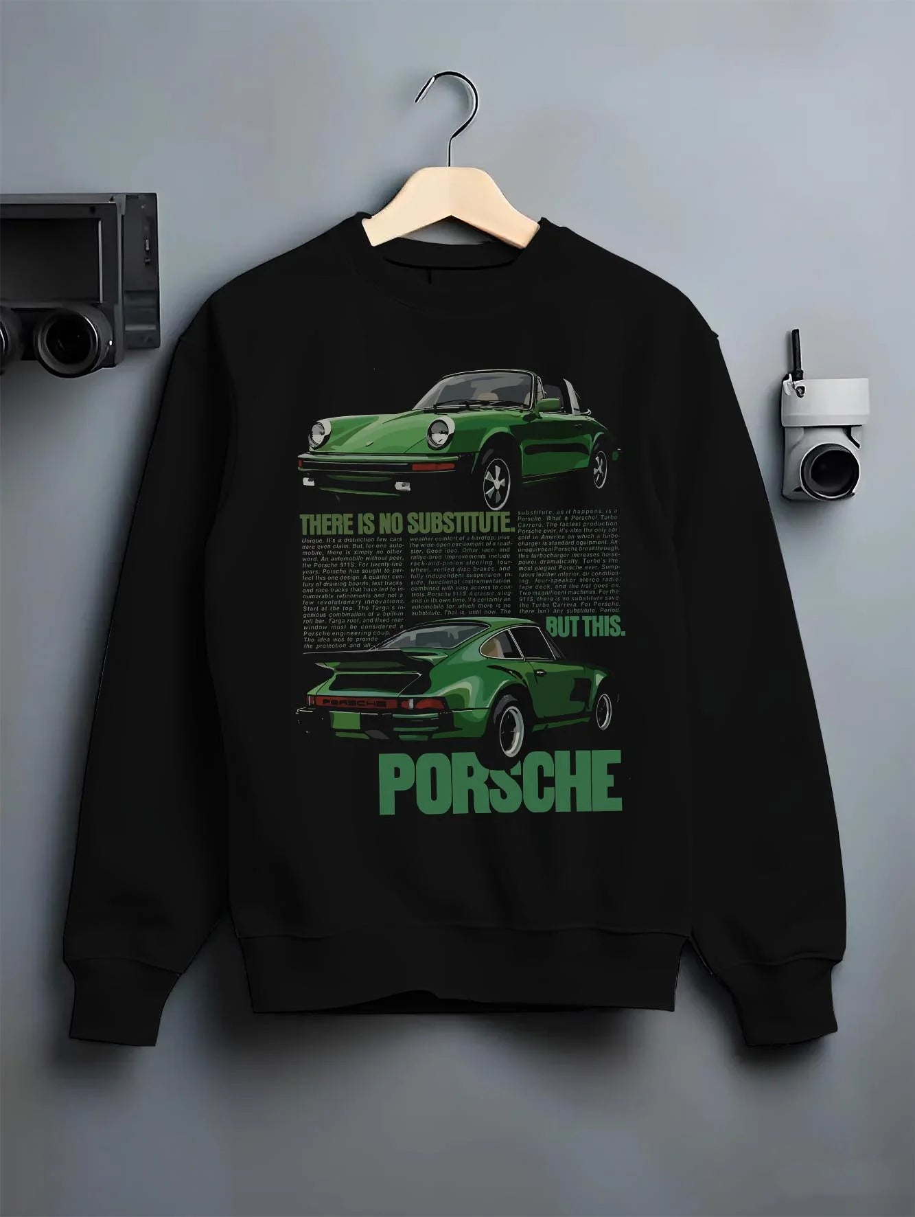 Black crewneck sweatshirt on a hanger against a grey wall, featuring Porsche 911 rs street retro vintage classic enthusiast graphic.
