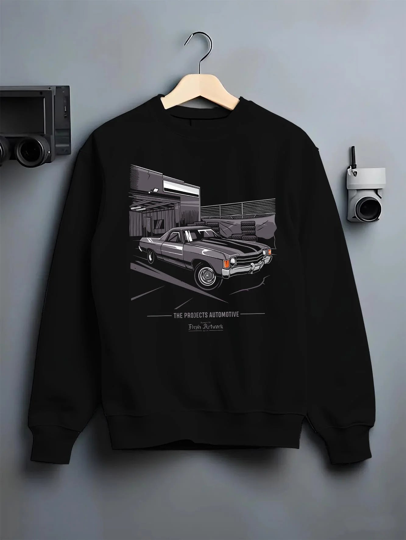 Black crewneck sweatshirt on a hanger against a grey wall, featuring CHEVROLET muscle retro classic enthusiast racing graphic.