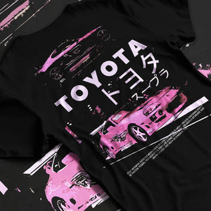 Black T-shirt laid flat with natural fabric folds, featuring Toyota Supra racing drift jdm japanese tuner street retro graphic.
