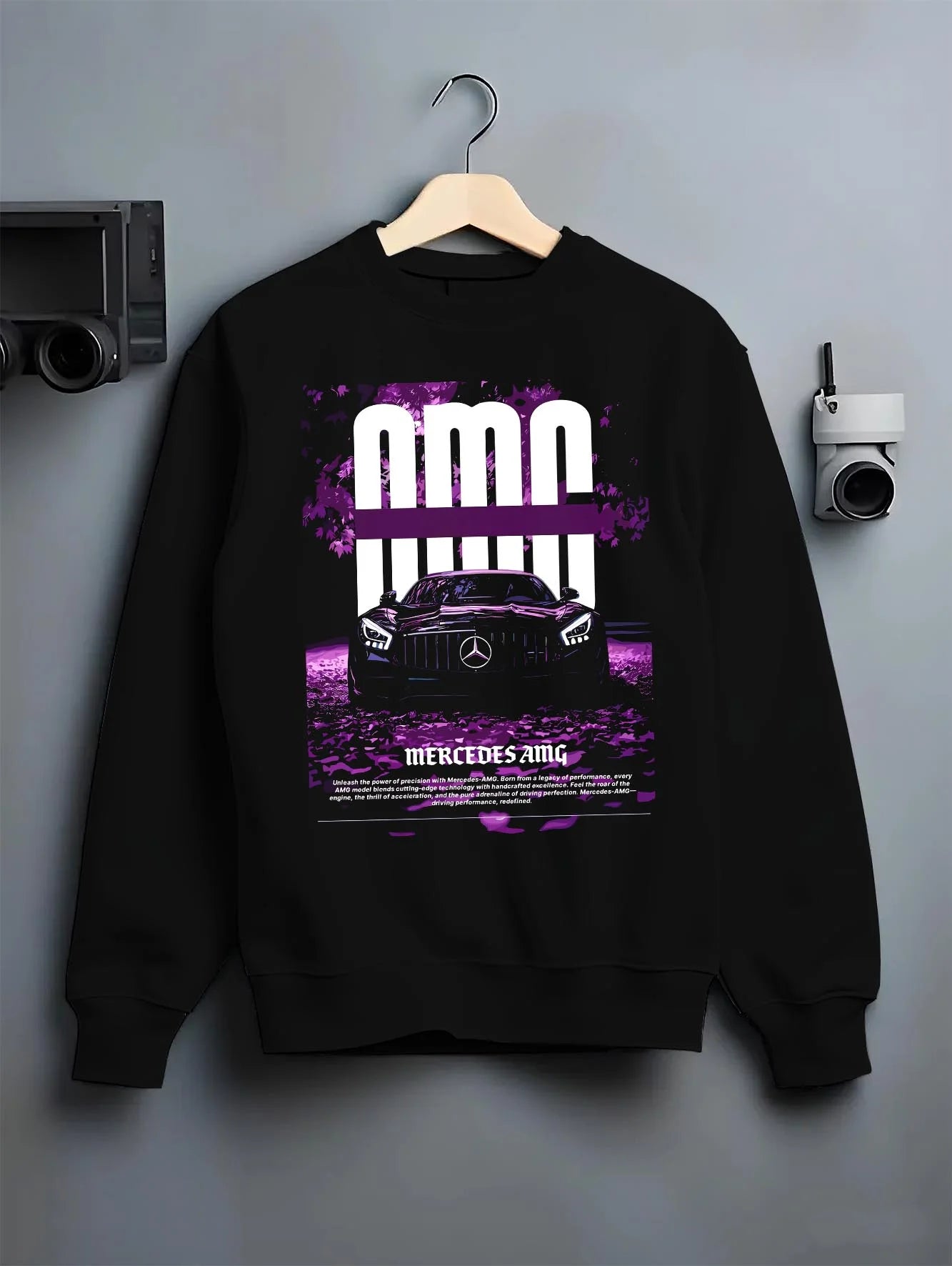 Black crewneck sweatshirt on a hanger against a grey wall, featuring Mercedes-Benz AMG racing street enthusiast performance graphic.