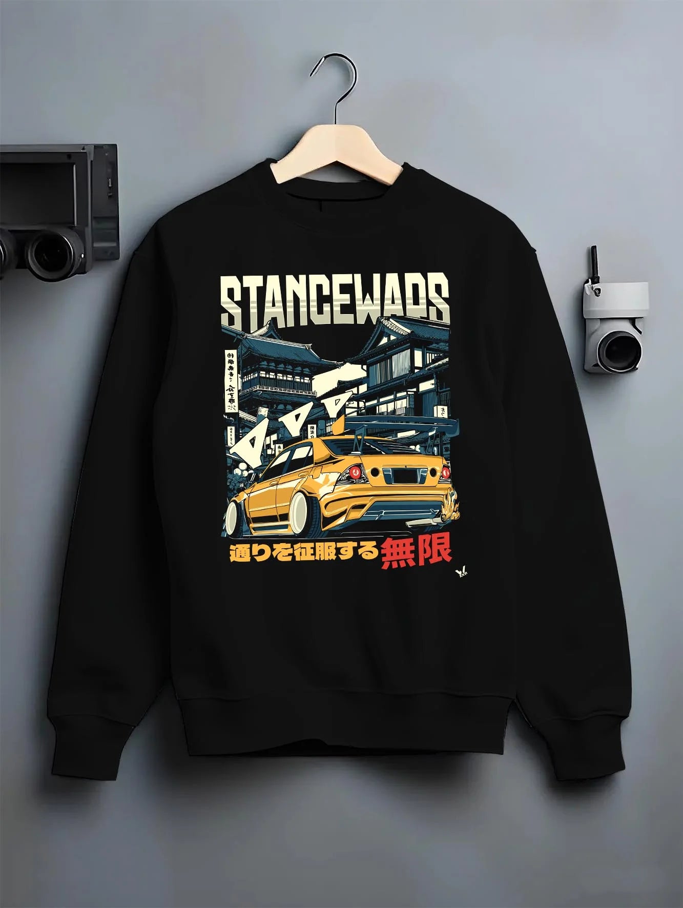Black crewneck sweatshirt on a hanger against a grey wall, featuring drift jdm tuner stance slammed stanced racing street graphic.
