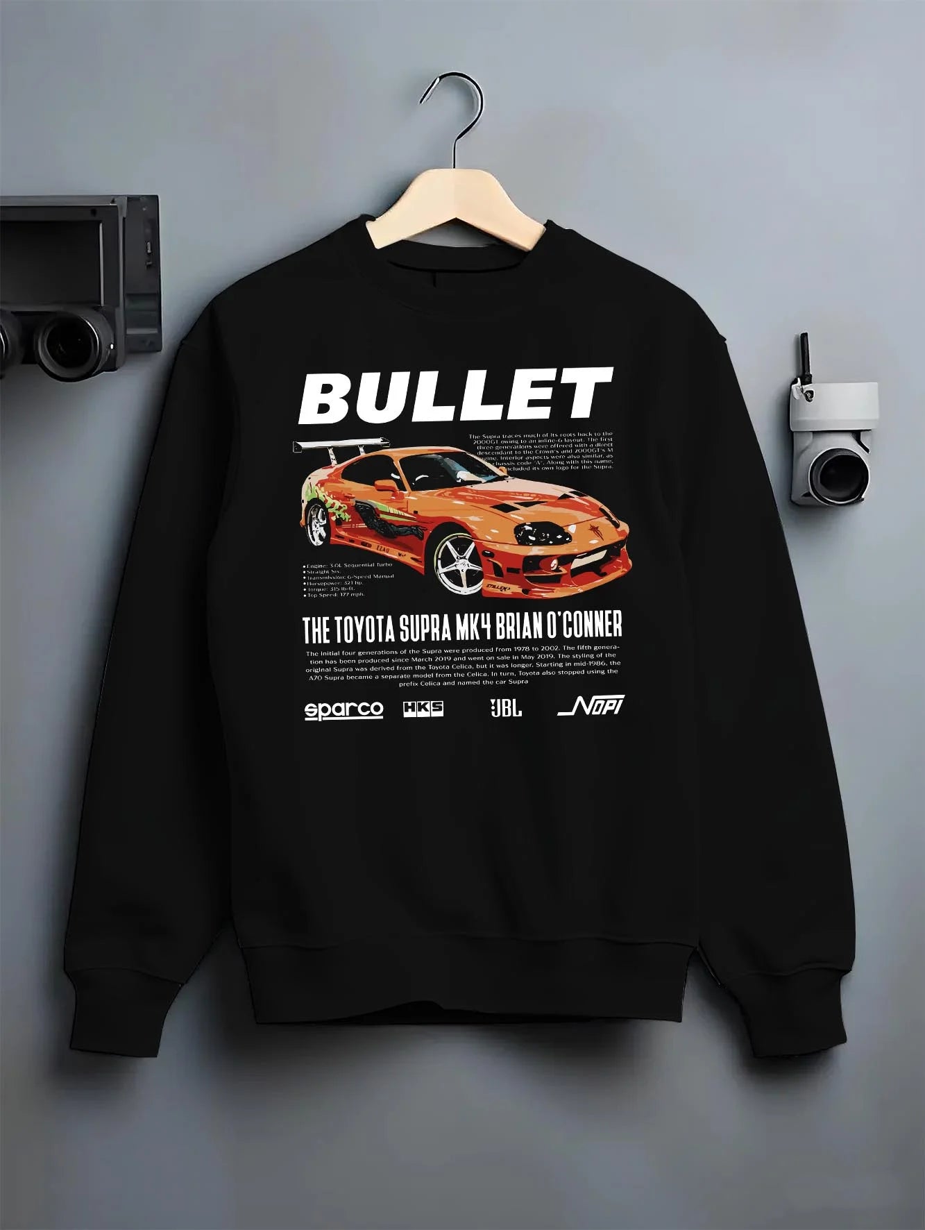 Black crewneck sweatshirt on a hanger against a grey wall, featuring Toyota Supra MK4 supra racing drift jdm tuner street graphic.