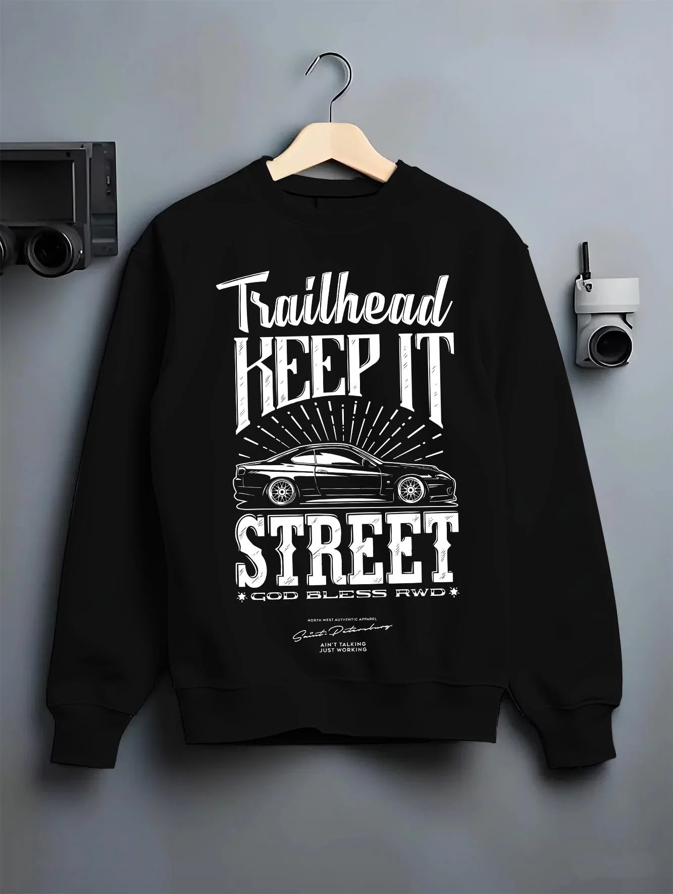 Black crewneck sweatshirt on a hanger against a grey wall, featuring rs racing race street enthusiast performance graphic.