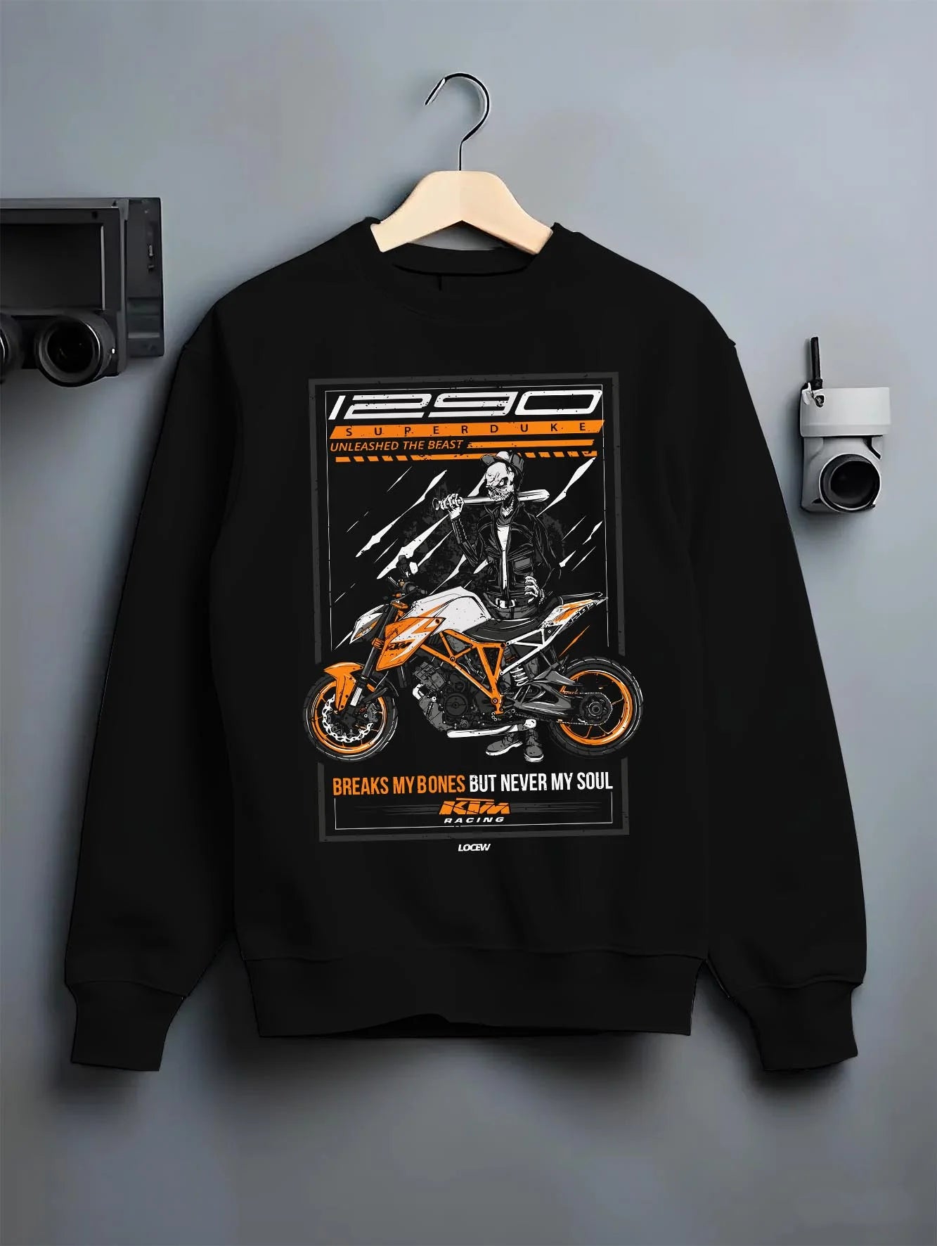 Black crewneck sweatshirt on a hanger against a grey wall, featuring KTM racing street beast performance motorsport graphic.