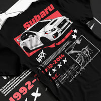 Black T-shirt laid flat with natural fabric folds, featuring Subaru WRX STI sti wrx turbo turbocharged racing rally graphic.