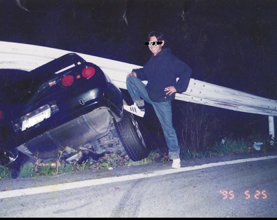 Retro JDM crash photo of car enthusiast posing beside drift car at night, vintage 90s aesthetic for Trackhead Apparel.