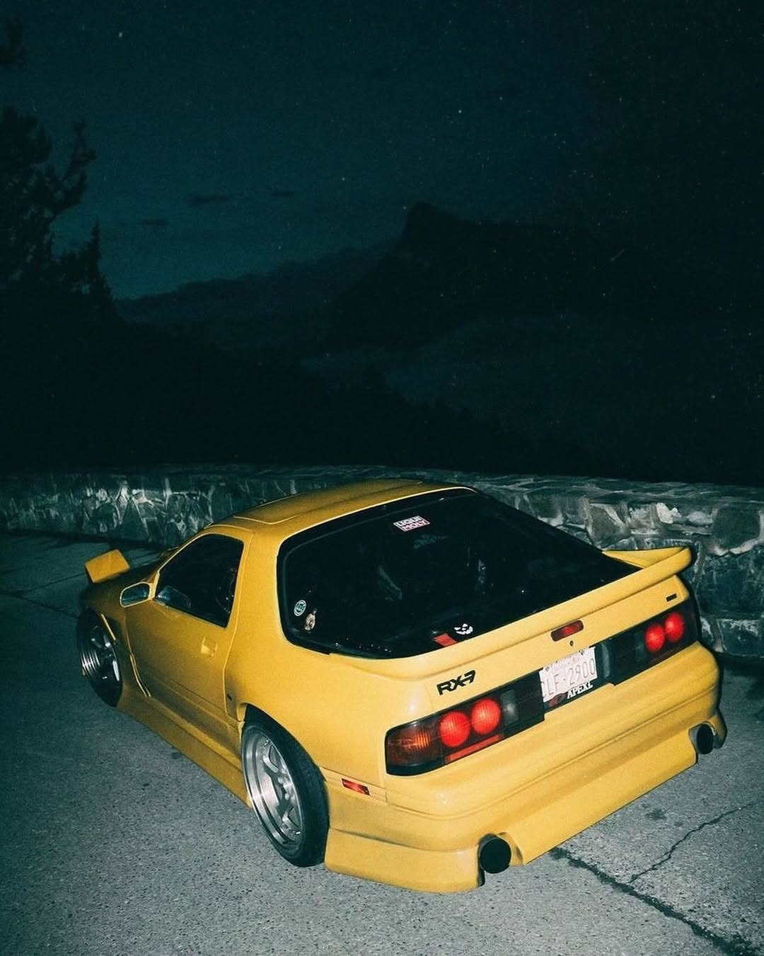 Yellow Mazda RX-7 FC parked on mountain road at night, JDM drift car aesthetic for Trackhead car enthusiasts.